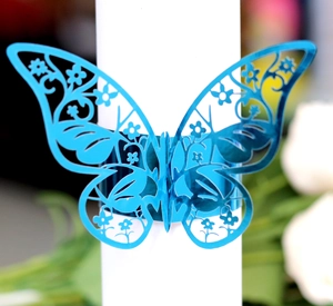 Macro detail of laser-cut bright blue butterfly napkin ring with hollow floral pattern
