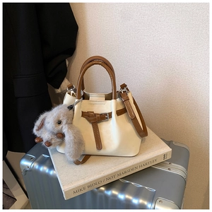 Close-up of cream and caramel leather tote bag with a cute plush rabbit pendant