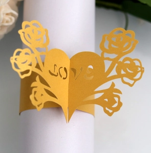Macro shot of gold laser-cut paper napkin ring featuring hollow heart and rose details