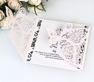 Detail of laser-cut butterfly wedding invitation in creamy white with intricate hollow patterns