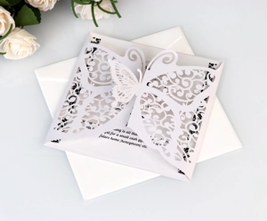 Close-up of laser-cut butterfly wedding invitation with envelope and floral decor