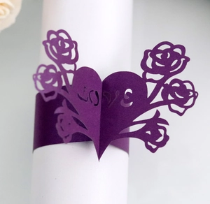 Detail of laser-cut paper napkin ring featuring purple rose and LOVE heart design