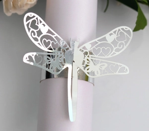 Macro view of dragonfly napkin ring with laser-cut heart pattern on pink linen