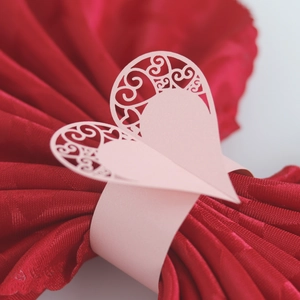 Close-up of pink laser-cut heart napkin ring with intricate floral patterns for party