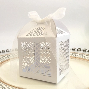 Elegant laser-cut pearl white candy gift box with sheer ribbon on a ceramic tray