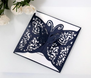 Macro detail of navy blue laser-cut butterfly invitation with sparkling glitter texture