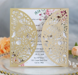 Detail of laser-cut burgundy wedding invitation with gold butterfly hollow pattern