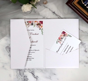 Macro detail of elegant white laser-cut wedding invitation with pink floral RSVP card insert
