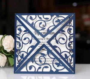 Close-up of laser-cut floral pattern on navy blue wedding invitation with white rose detail