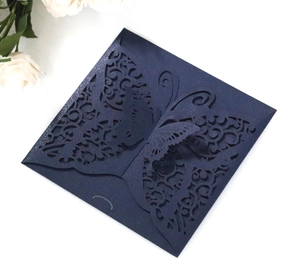Macro detail of laser-cut navy blue wedding invitation with 3D butterfly and glitter finish