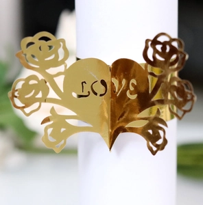 Close-up of golden laser-cut napkin ring with rose and heart LOVE hollowed design