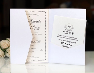 Close-up of pearl white laser-cut wedding invitation set with floral RSVP card