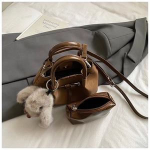 Close-up of retro brown bucket bag set with mini pouch and plush bunny charm detail