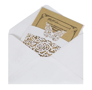 Close-up of laser-cut rose and butterfly hollow patterns on a white wedding invitation