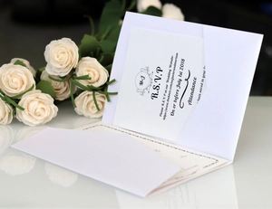 Detail of elegant white wedding RSVP card with envelope and floral background