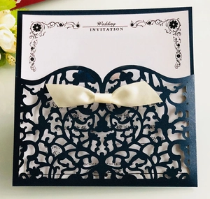 Détail d'invitation de mariage bleue découpée au laser avec un élégant nœud en soie blanc
