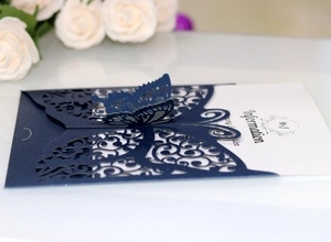 Detail of laser-cut butterfly invitation card in navy blue with fine hollowed pattern