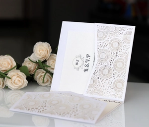 Macro shot of laser-cut floral wedding invitation with cream paper and RSVP card detail