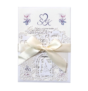 Detail of laser-cut wedding invitation featuring elegant carriage and ribbon bow
