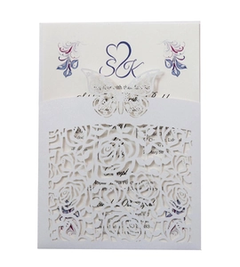 Macro detail of laser-cut floral patterns and 3D butterfly on a wedding invitation set
