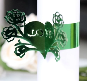 Macro shot of green laser-cut paper napkin ring with rose and LOVE heart design