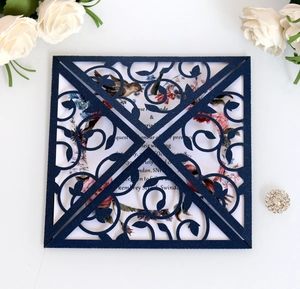 Navy blue laser-cut wedding invitation with intricate vine patterns and floral inner card
