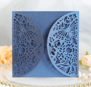 Detail of laser-cut butterfly invitations in dark blue pearlescent paper with floral motifs