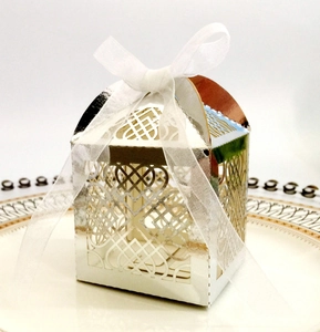 Detail of silver laser-cut chocolate box with intricate heart patterns and white ribbon