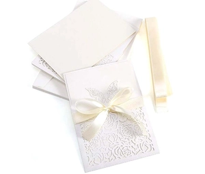 Macro shot of laser-cut rose hollow invitation with elegant cream ribbon and pearl finish
