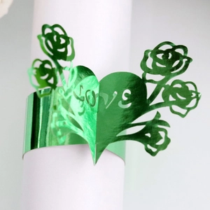 Detail of green laser-cut LOVE napkin ring with rose and heart pattern on white holder
