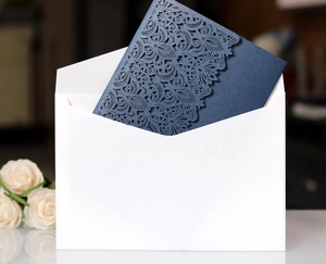 Detail of laser-cut floral wedding invitation in navy blue with a white envelope