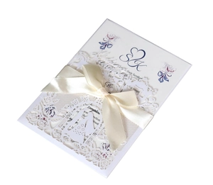 Detailed laser-cut floral pattern with white satin ribbon on a wedding invitation