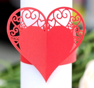 Close-up of red heart laser-cut paper napkin ring with elegant floral filigree pattern
