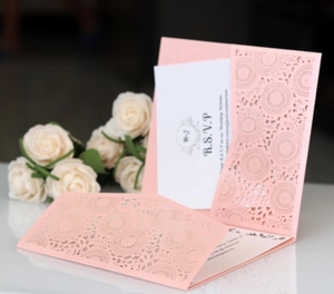 Close-up of laser-cut lavender square invitation with intricate mandala floral patterns