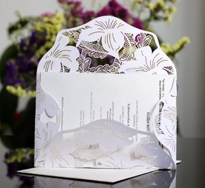 Close-up of laser-cut lily patterns on white invitation card with printing insert