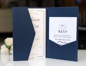 Detail of dark blue kraft wedding invitation with pearlescent RSVP cards and floral accents