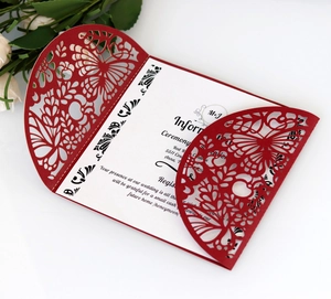 Detail of laser-cut burgundy invitation featuring intricate butterfly and floral patterns