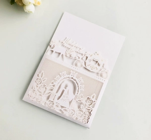 Macro detail of laser-cut wedding invitation featuring elegant white floral lace patterns