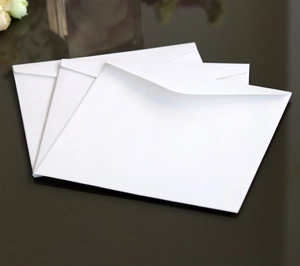 Detail view of square white laser-cut wedding invitation envelopes with smooth paper texture