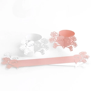 Macro shot of laser-cut rose and love heart paper napkin rings in pink and white