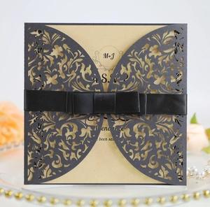 Detailed laser-cut grey invitation sleeve with butterfly wing pattern and black ribbon bow