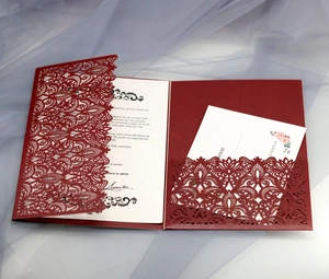 Macro detail of laser-cut burgundy invitation with intricate floral vine patterns