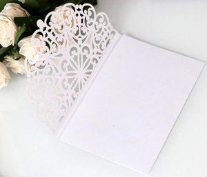 Macro view of white laser-cut floral lace invitation cover with blank inner card
