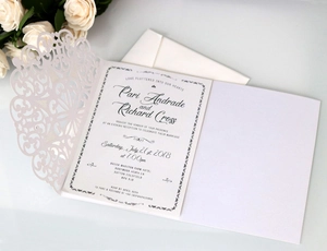 Detailed laser-cut wedding invitation set with floral cover and white envelope