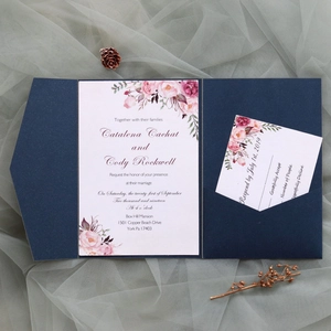 Flat lay of navy blue laser-cut wedding invitation set with floral cards and pine cones