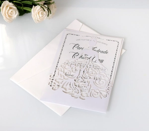 Detail van lasergesneden huwelijksuitnodiging met trouwjurkpatroon op wit parelmoer papier