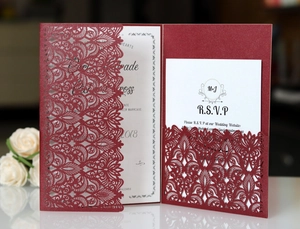 Macro view of burgundy laser-cut lace wedding invitation with pearlescent floral cover