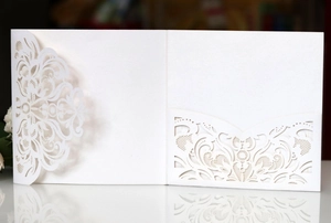 Close-up of laser-cut floral pattern on white wedding invitation card with textured paper