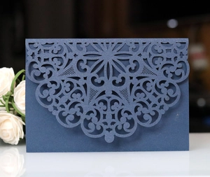 Navy blue laser cut mandala invitation envelope on white reflective surface with flower