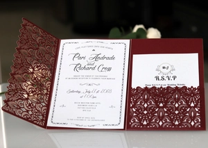 Detail of laser-cut burgundy lace wedding invitation with elegant printed white insert card